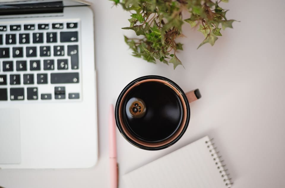 A desk from above with coffee and a notebook