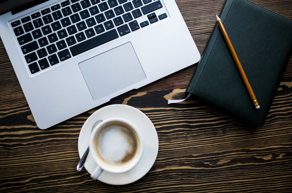 A writer's desk with a laptop and coffee